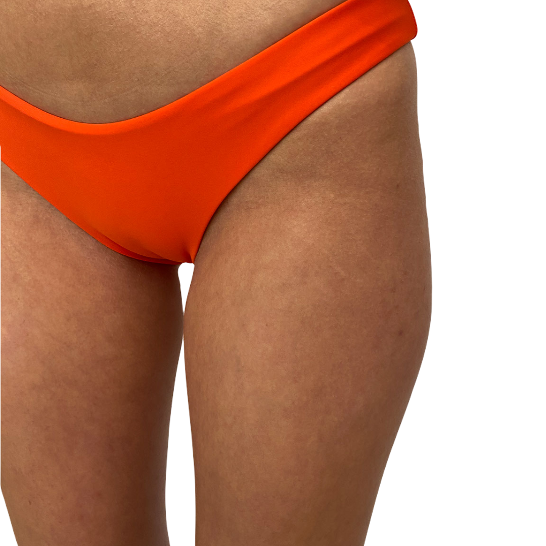 An orange bikini bottom with a cheeky cut, V dip front design, made from OEKO-TEX certified fabric.